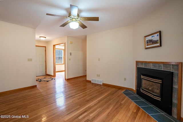 unfurnished living room featuring light wood-style flooring, baseboards, visible vents, a ceiling fan, and a fireplace