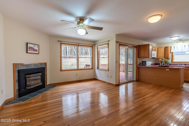 unfurnished living room with light wood-style flooring, baseboards, a sink, and ceiling fan