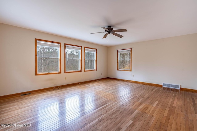 spare room with light wood-type flooring, visible vents, baseboards, and ceiling fan