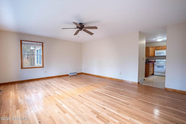 spare room featuring light wood-type flooring, baseboards, visible vents, and ceiling fan