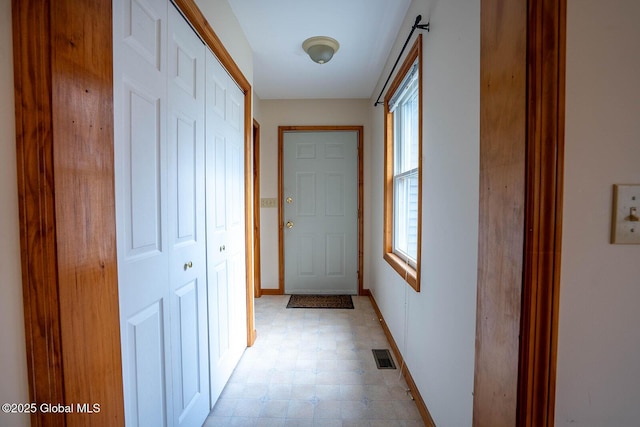 corridor with light floors, baseboards, visible vents, and a healthy amount of sunlight