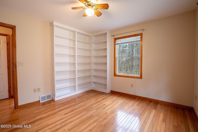 unfurnished room featuring visible vents, a ceiling fan, light wood-type flooring, baseboards, and built in features