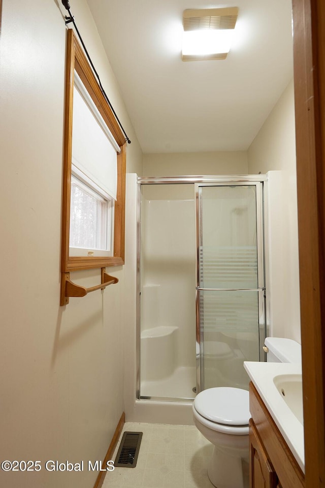 bathroom featuring a shower stall, toilet, vanity, baseboards, and visible vents