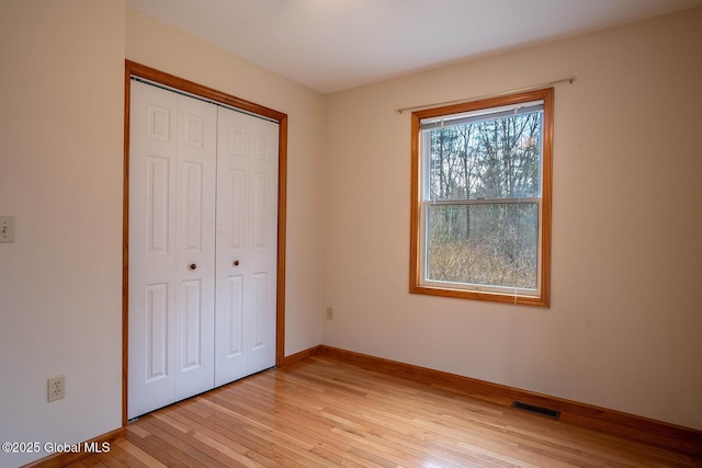 unfurnished bedroom with a closet, light wood-type flooring, visible vents, and baseboards