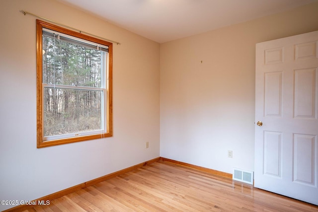 empty room featuring light wood-style floors, visible vents, and baseboards