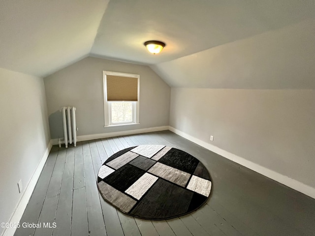 additional living space featuring radiator heating unit, baseboards, hardwood / wood-style flooring, and vaulted ceiling