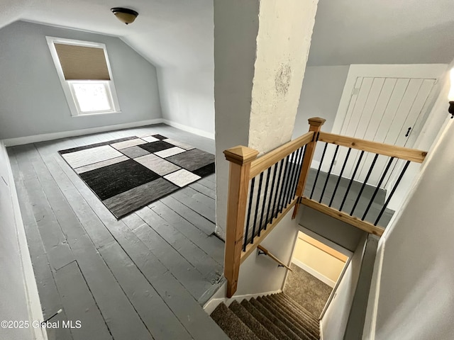 staircase with baseboards, hardwood / wood-style floors, and vaulted ceiling