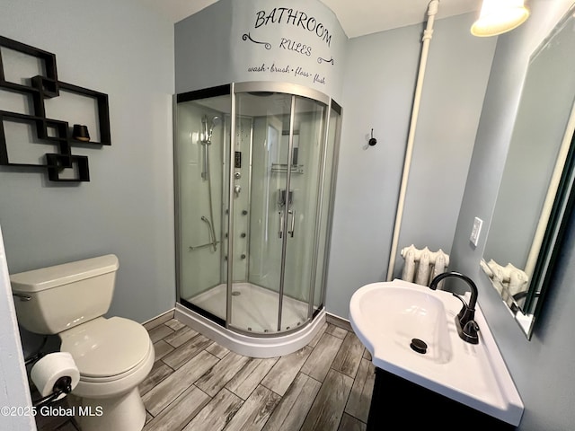 full bath featuring toilet, baseboards, a stall shower, and wood tiled floor