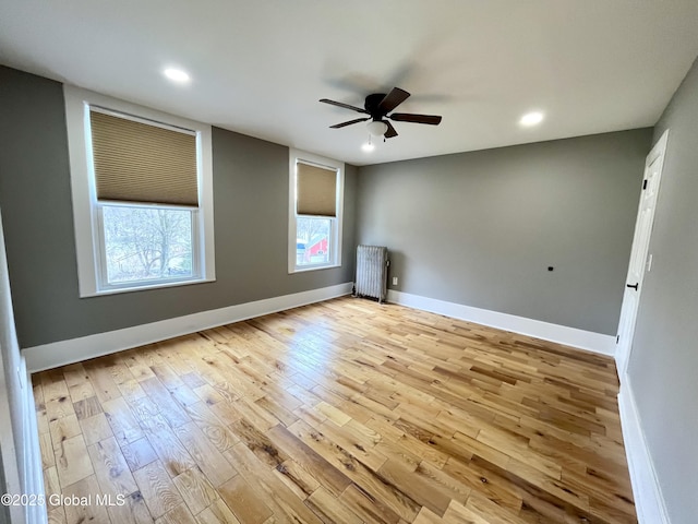 empty room featuring baseboards, recessed lighting, radiator heating unit, ceiling fan, and wood finished floors
