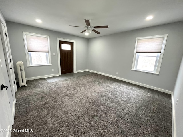 interior space featuring radiator heating unit, dark colored carpet, a wealth of natural light, and ceiling fan