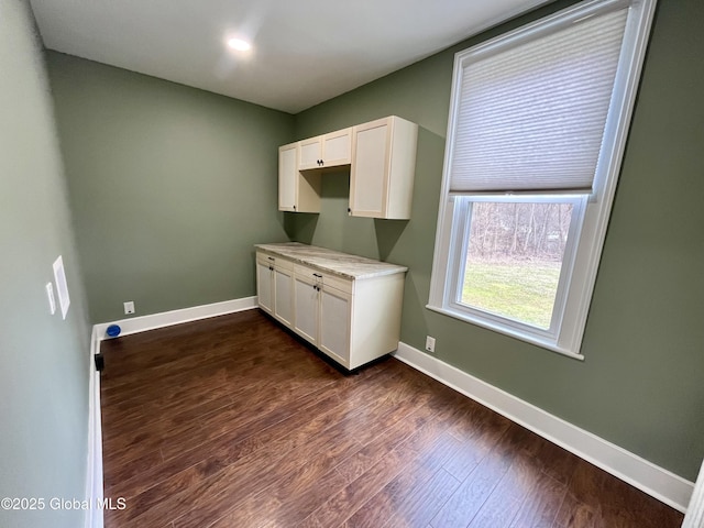 laundry area with dark wood-style flooring and baseboards