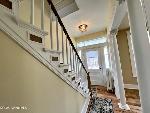 entrance foyer featuring light wood-style floors, decorative columns, baseboards, and stairway