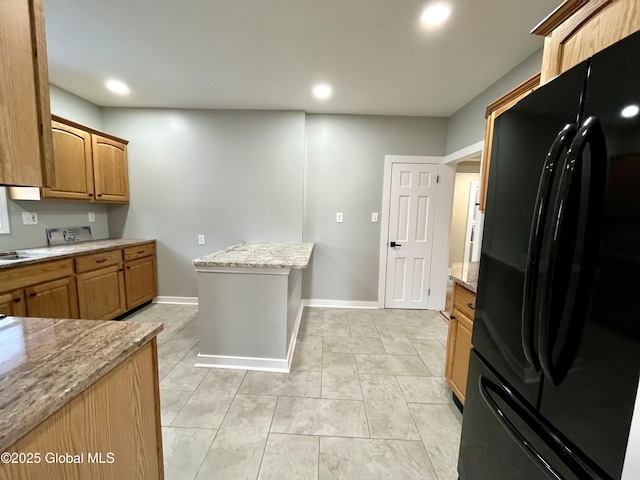 kitchen featuring recessed lighting, light stone countertops, baseboards, and freestanding refrigerator