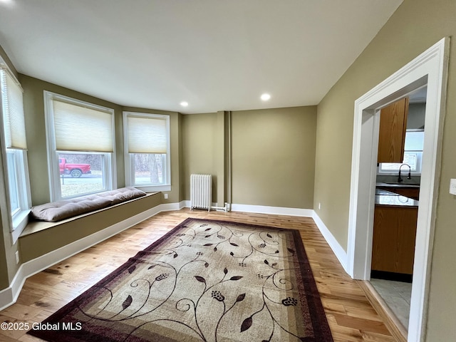 interior space featuring light wood-type flooring, baseboards, recessed lighting, radiator heating unit, and a sink