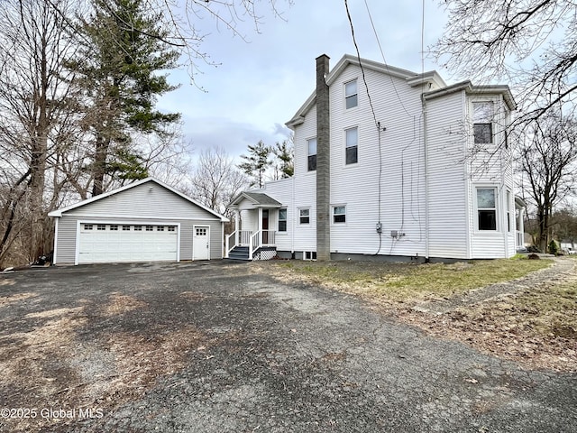 view of side of property featuring an outdoor structure, a garage, and a chimney