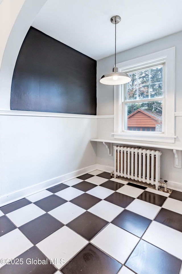 unfurnished dining area featuring radiator and baseboards