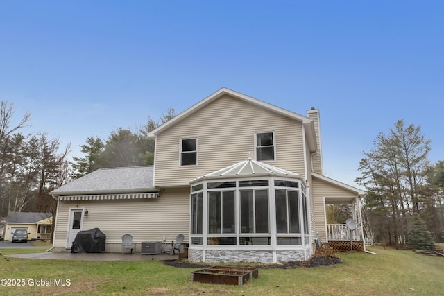 rear view of property featuring a chimney, roof with shingles, a lawn, central AC unit, and a sunroom