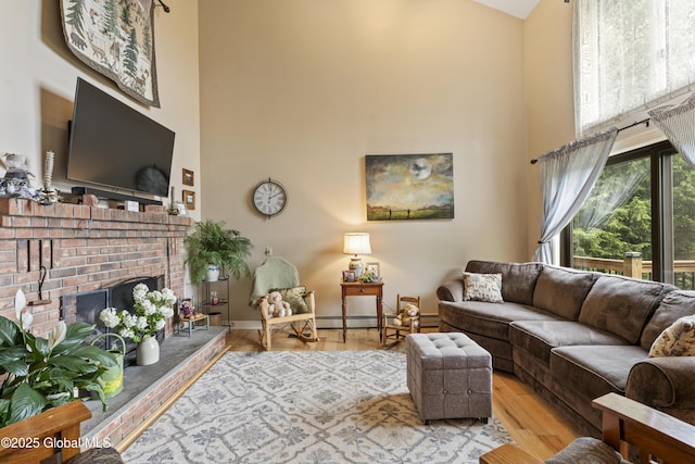 66 Schaeffer Rd, Berlin, NY 12138 - living area featuring a towering ceiling, wood finished floors, a brick fireplace, and baseboard heating