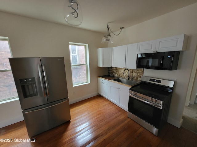 kitchen featuring tasteful backsplash, light wood-type flooring, white cabinets, appliances with stainless steel finishes, and a sink