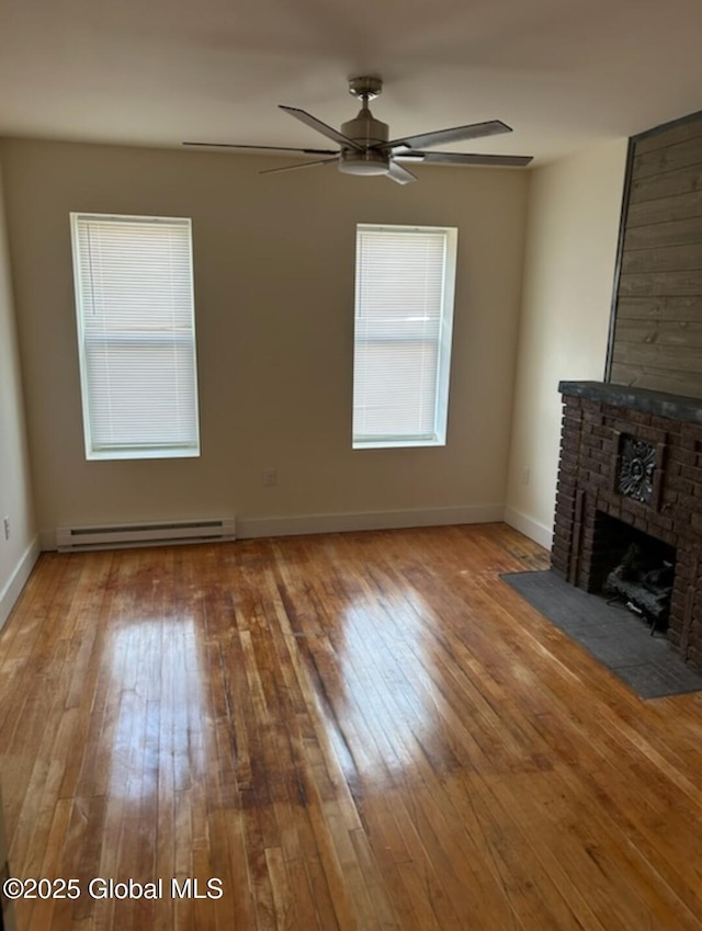 unfurnished living room with baseboards, a ceiling fan, hardwood / wood-style flooring, a fireplace, and a baseboard heating unit