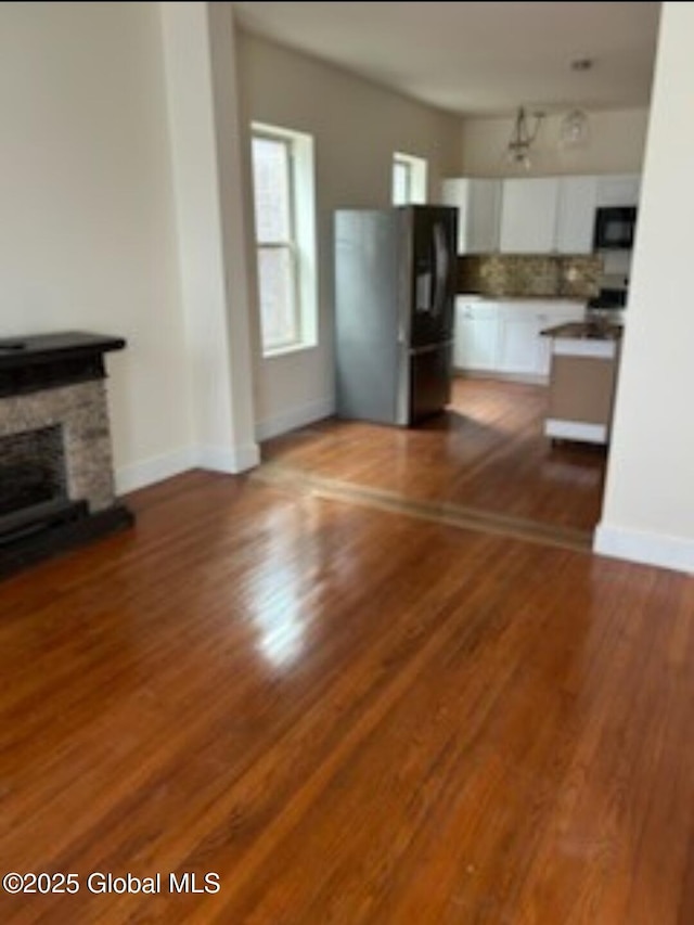 unfurnished living room with wood finished floors, a fireplace, and baseboards