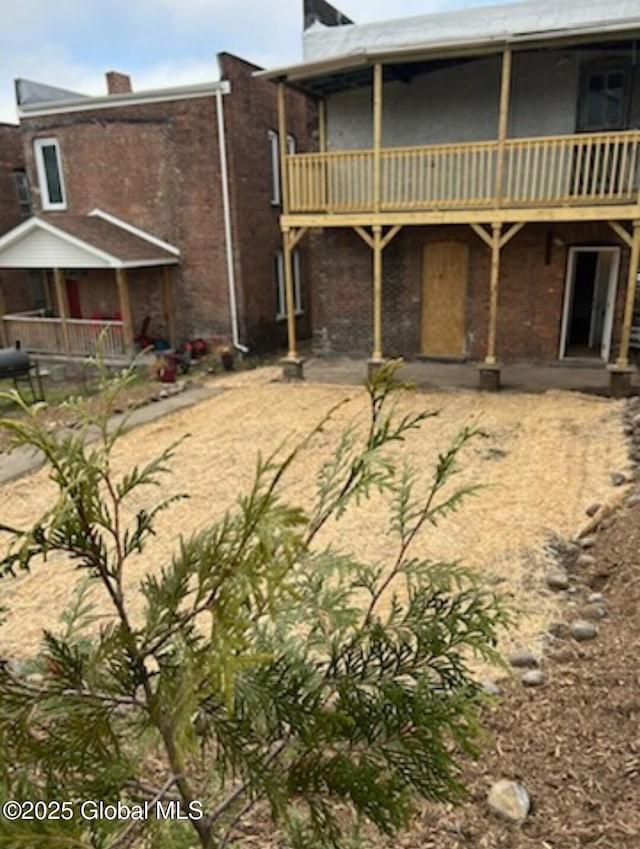 back of property featuring a chimney and brick siding