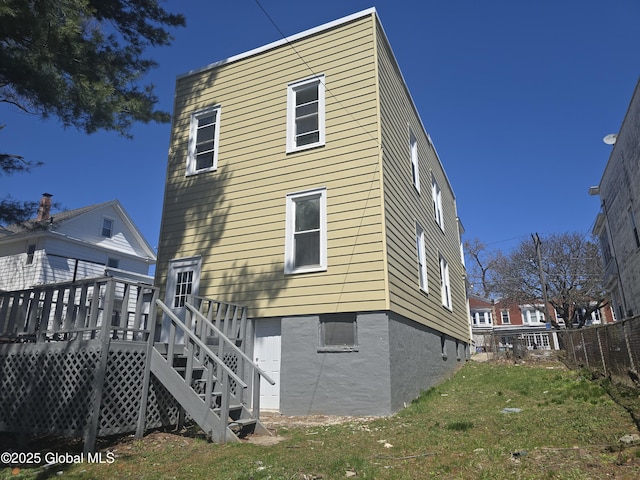 back of house with fence, a wooden deck, and a yard