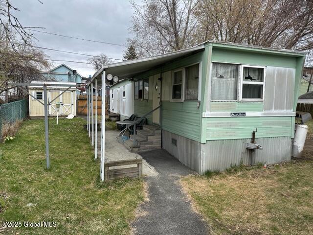 view of front of home featuring fence, a storage unit, an outdoor structure, and a front yard