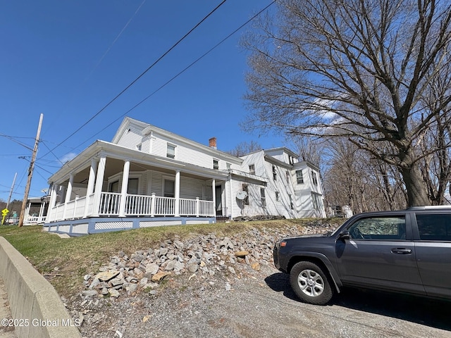 view of property exterior featuring a chimney and covered porch