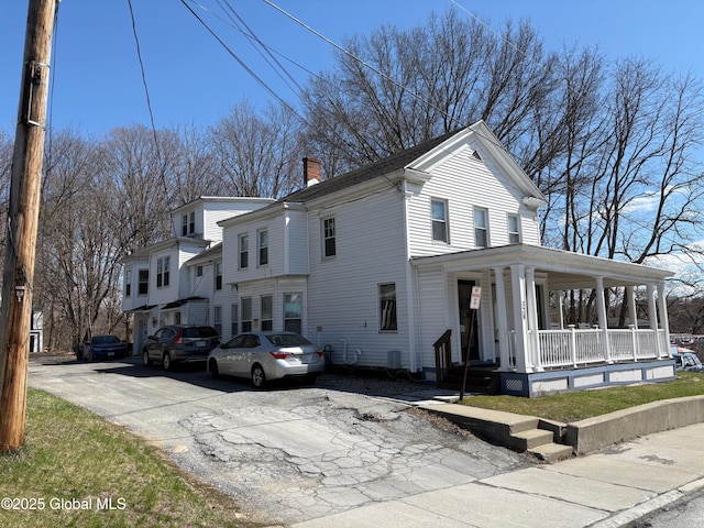 view of side of home featuring a porch and a chimney