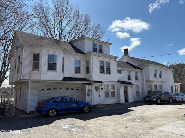 townhome / multi-family property featuring driveway, a chimney, and an attached garage
