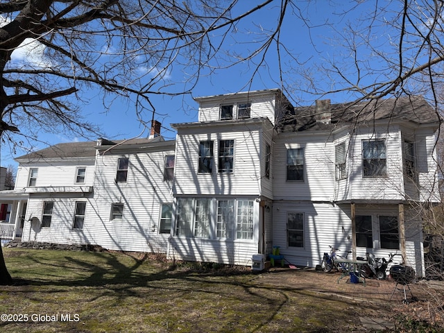 back of house with a yard, central AC unit, and a chimney