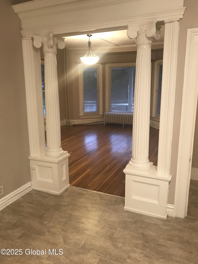 interior space featuring radiator heating unit, baseboards, wood finished floors, and decorative columns