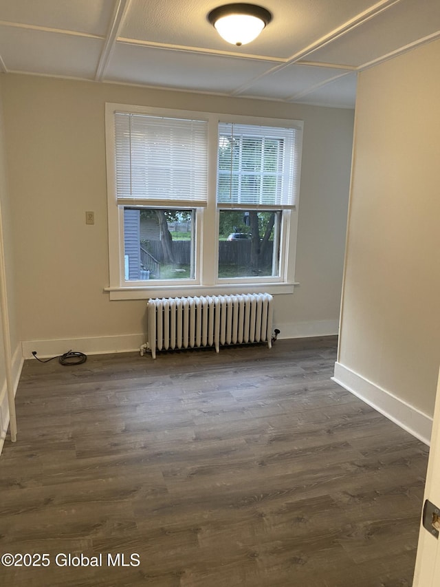 spare room with radiator, dark wood finished floors, and baseboards
