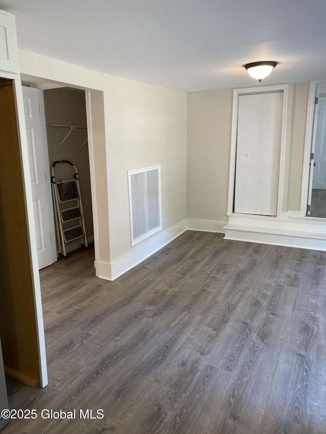 empty room featuring baseboards, visible vents, and dark wood-style floors