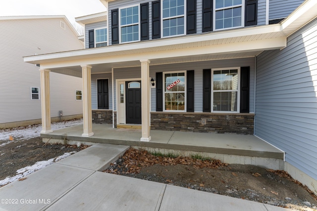 entrance to property featuring a porch and stone siding