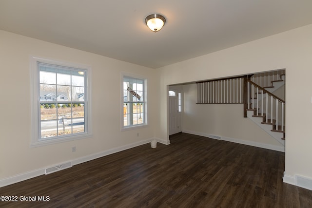 foyer featuring baseboards, dark wood-style floors, visible vents, and stairway