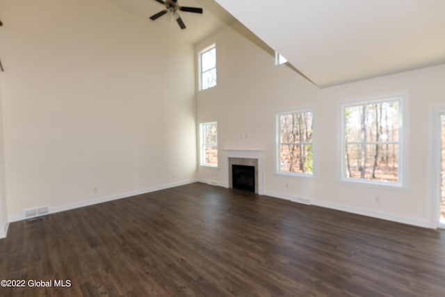 unfurnished living room with baseboards, a fireplace, a ceiling fan, dark wood-type flooring, and high vaulted ceiling
