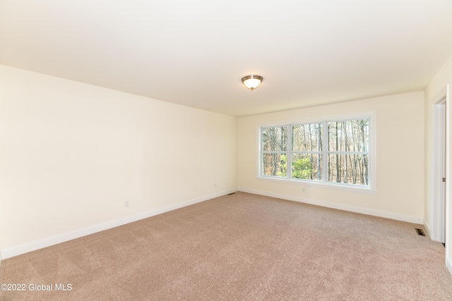 spare room with light carpet, baseboards, and visible vents