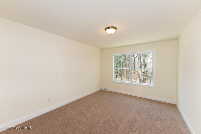 spare room featuring light carpet, baseboards, and visible vents