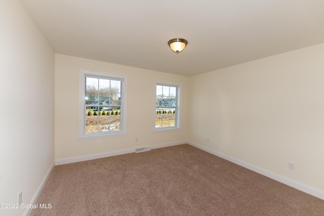 spare room with visible vents, baseboards, and light colored carpet