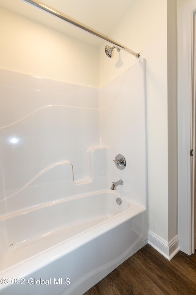 bathroom featuring washtub / shower combination, baseboards, and wood finished floors