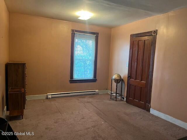 carpeted spare room with baseboard heating and baseboards