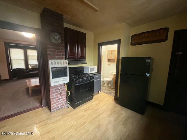 kitchen with dark brown cabinetry, light wood-style floors, black appliances, and heating unit