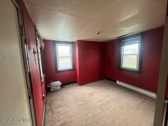 spare room featuring baseboards, a baseboard heating unit, and light colored carpet