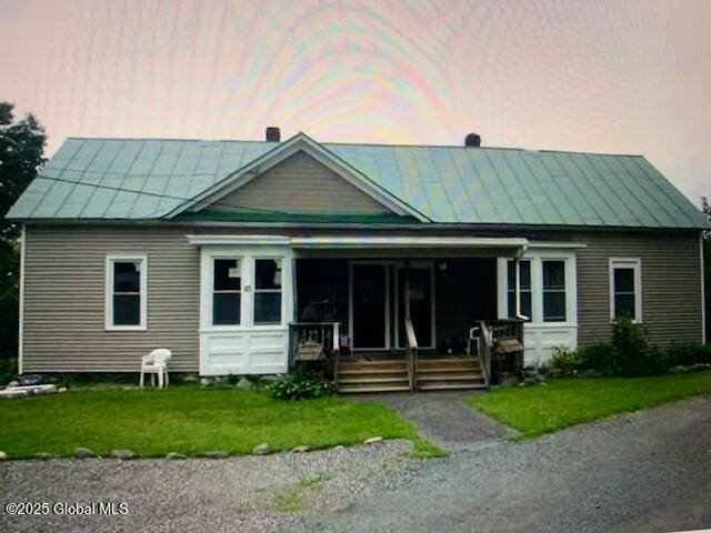 view of front of property featuring a porch, a standing seam roof, a front yard, and metal roof
