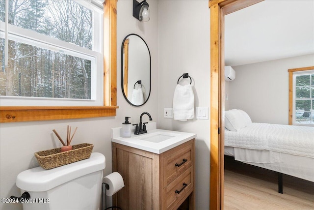 bathroom featuring vanity, ensuite bath, toilet, a wall unit AC, and wood finished floors
