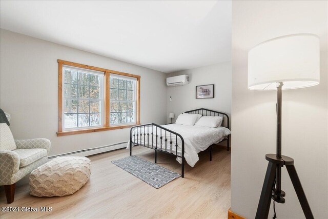 bedroom featuring a baseboard radiator, wood finished floors, and a wall mounted air conditioner