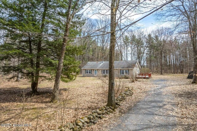 view of front of home with aphalt driveway and a view of trees