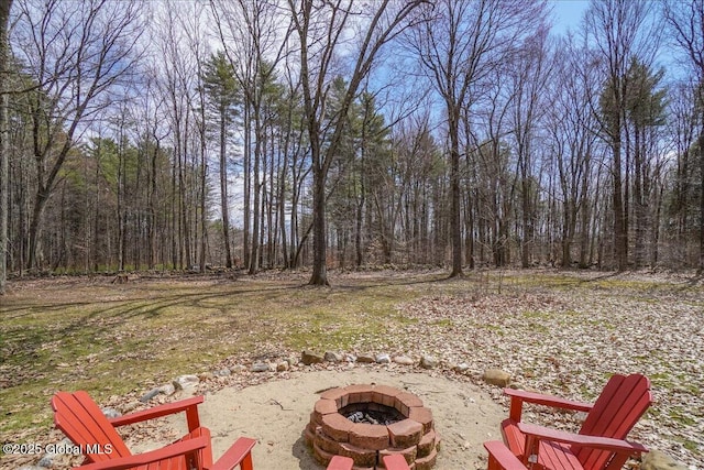view of yard featuring a view of trees and a fire pit
